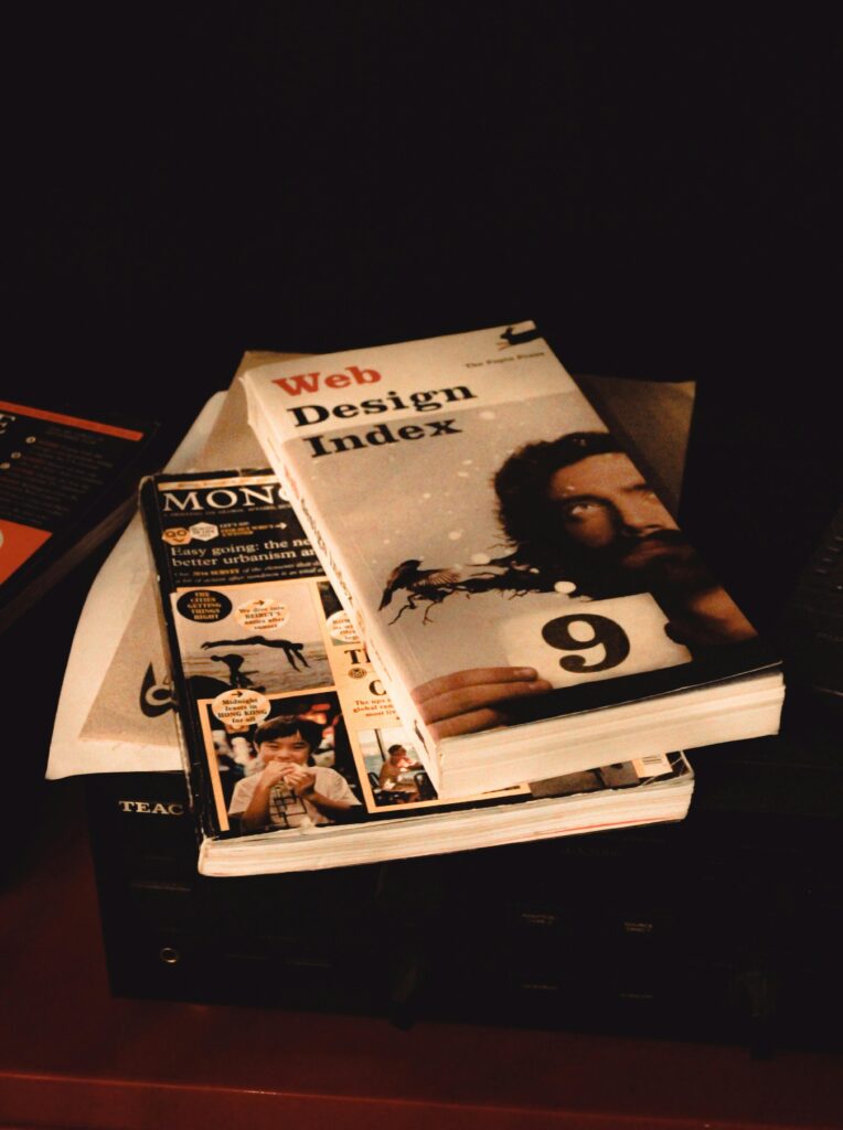 Stack of web design and media books on a shelf, emphasizing creative exploration.